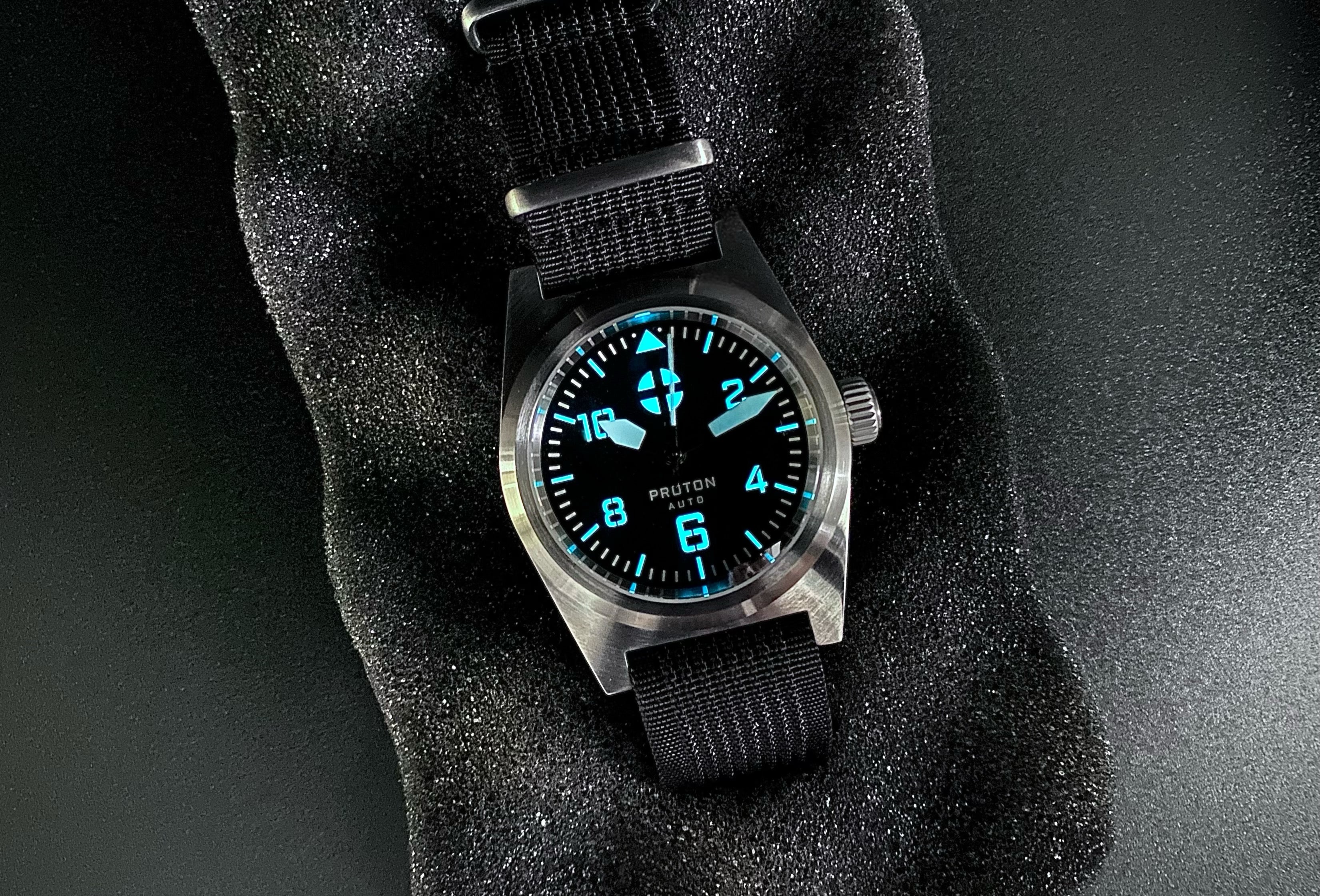 Mechanical men's field watch with lumed dial and hands on black nylon strap
