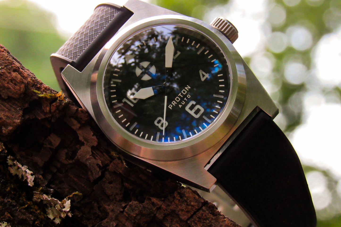 Automatic men's watch with black strap and silver case on a wooden surface with blurred background